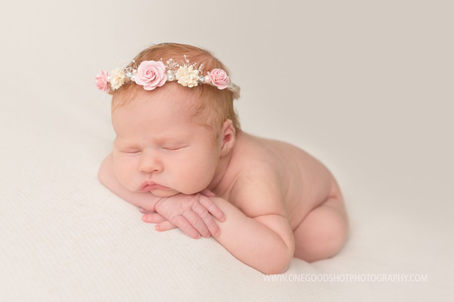 newborn girl, head on hands, floral halo, pink and white