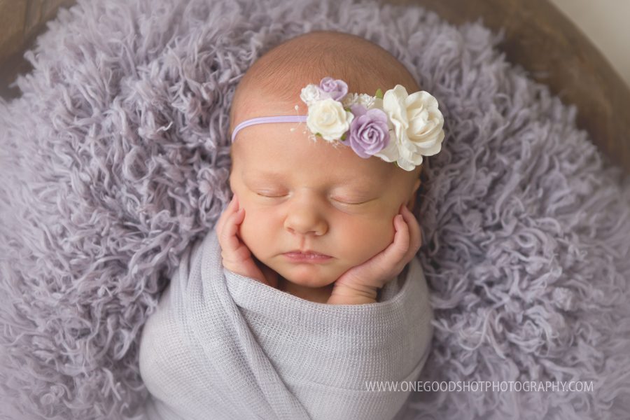 newborn baby girl, hands on cheeks, lavender wrap, floral headband