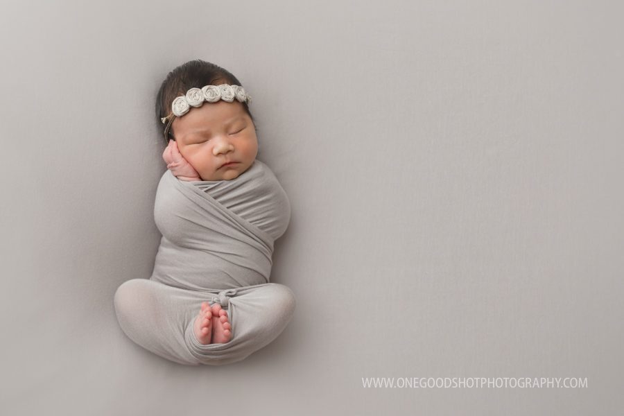 Newborn girl, wrapped in taupe on taupe back drop