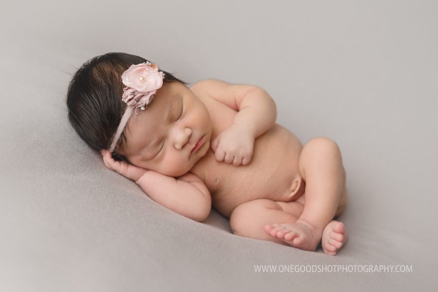 Newborn girl, side lying pose, taupe backdrop