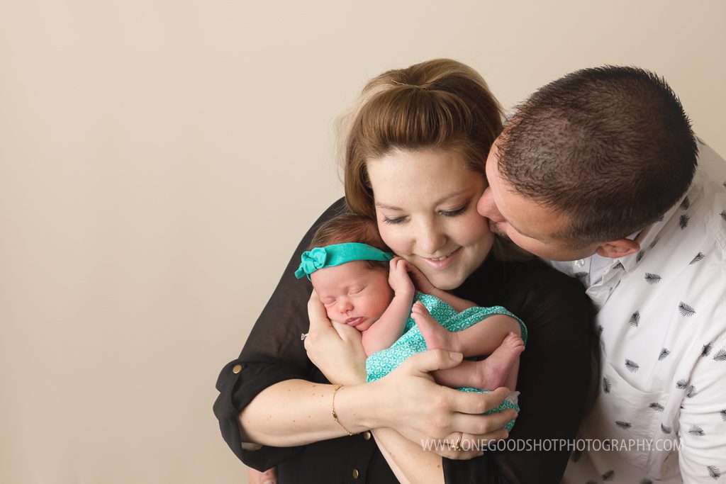 Newborn family picture, dad kissing mom on cheek