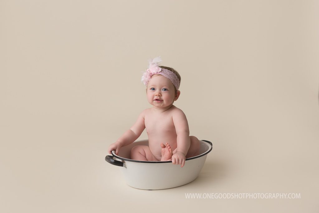 One year old girl in vintage wash basin with pink bow