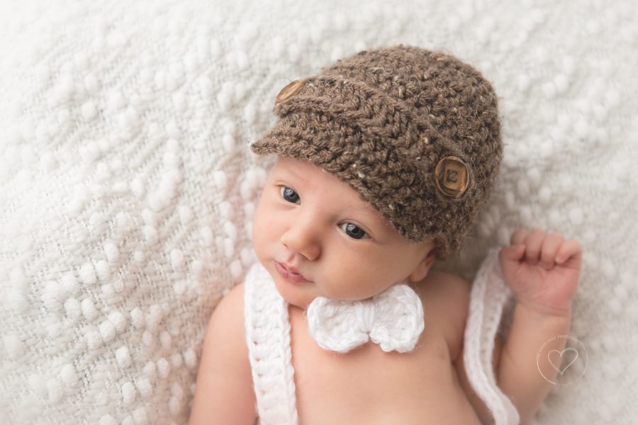 newborn boy, newsboy hat, crochet bowtie and suspenders, awake baby