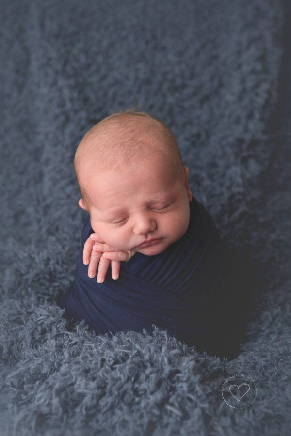 newborn boy, wrapped in navy blanket,  potato sack pose