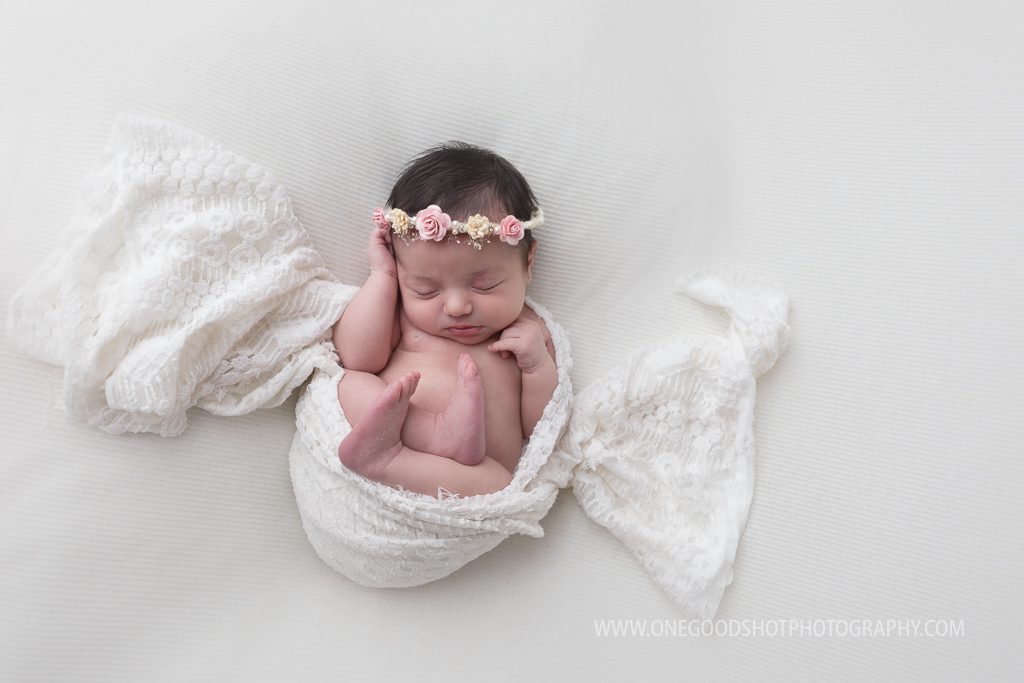 newborn girl wrapped in lace wearing floral halo