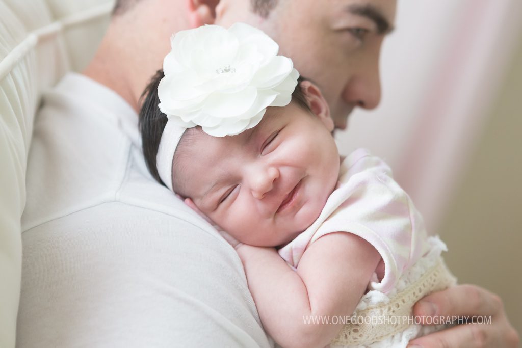 newborn girl smiling on daddy's shoulder in rocking chair