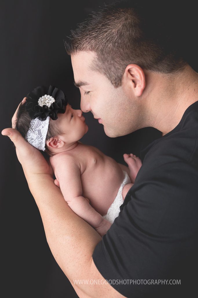 daddy holding newborn girl nose to nose, profile picture, dressed in black