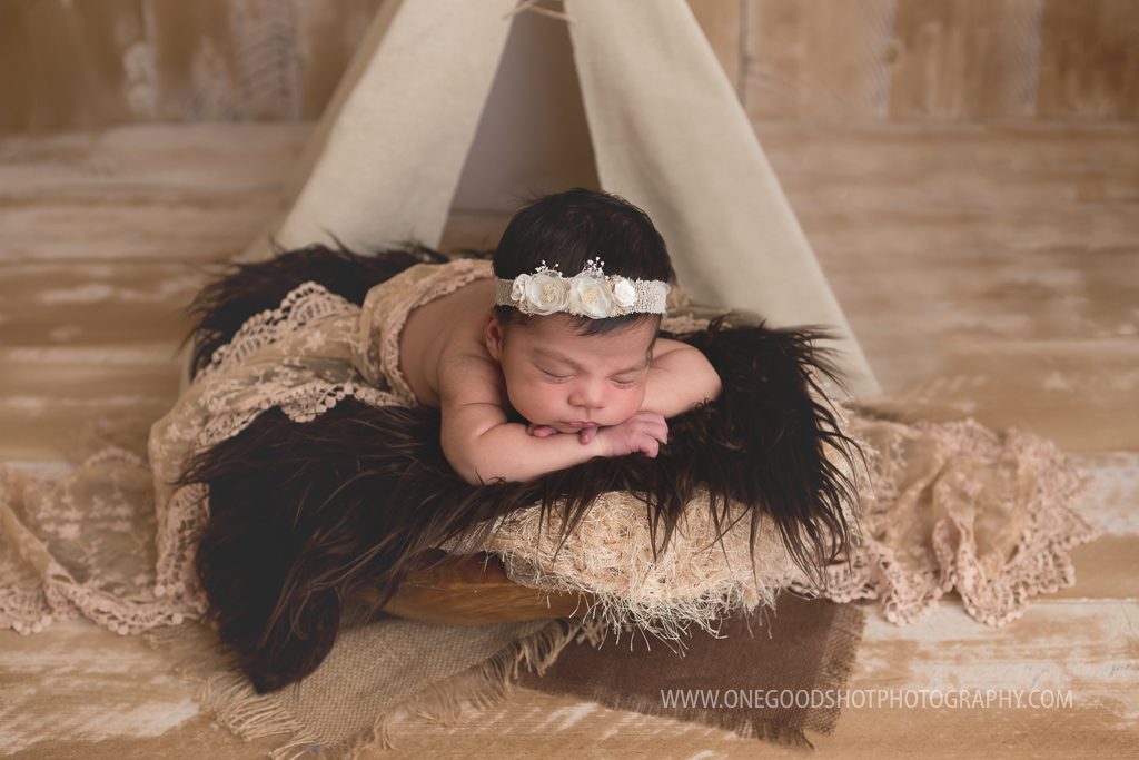 newborn girl, head on hands in a bowl, teepee prop, american indian