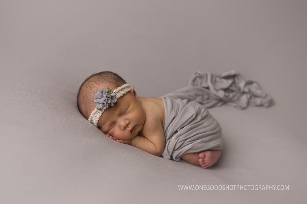 newborn girl in the bum up pose covered with a gray wrap on a gray backdrop,fresno photographer