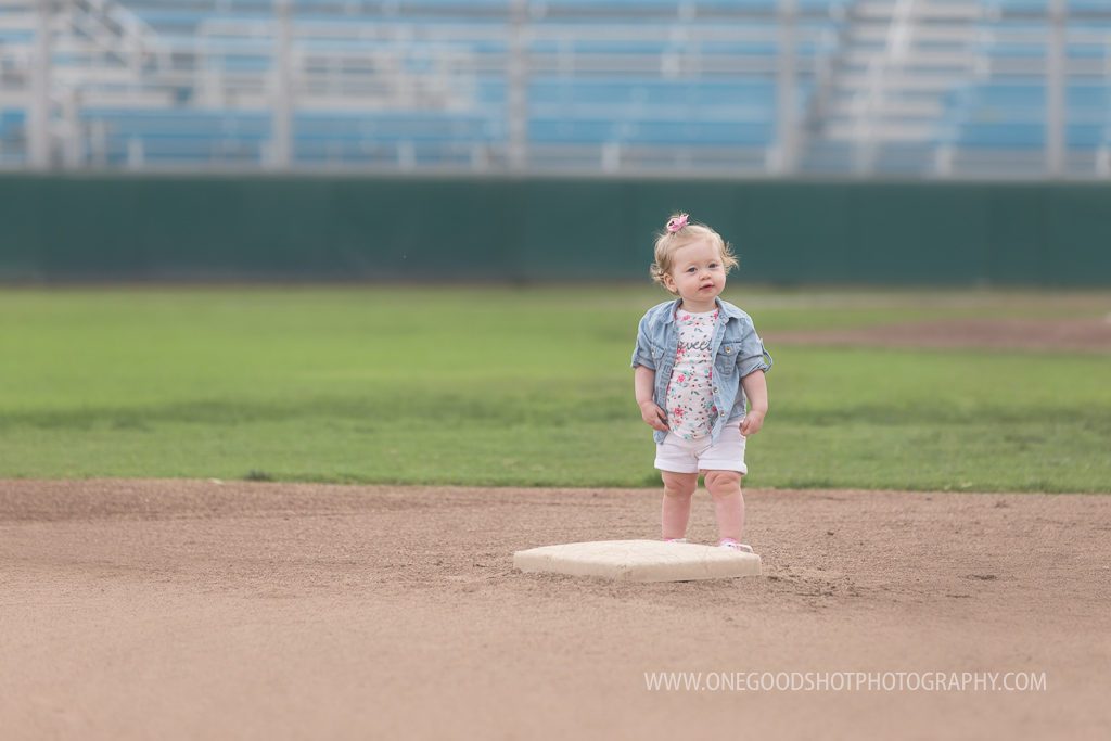 2 year old in the outfield on baseball field, 2nd base
