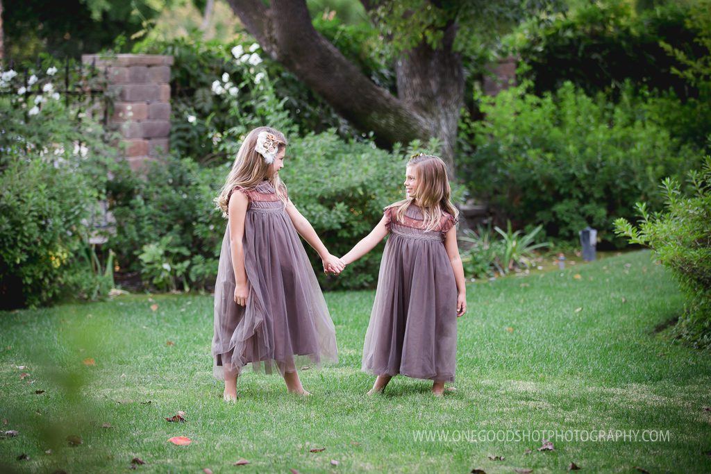 sisters, hugging, holding hands, wearing vintage brown dress in a beautiful green garden