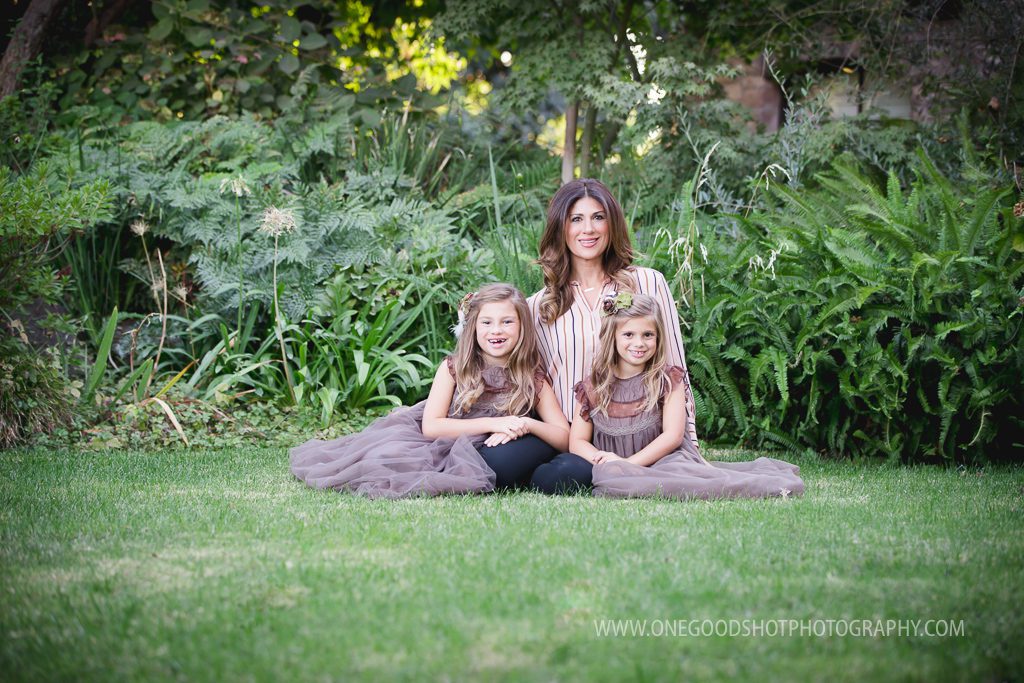 Mother and daughters wearing vintage taupe, brown dress, sitting in a the garden