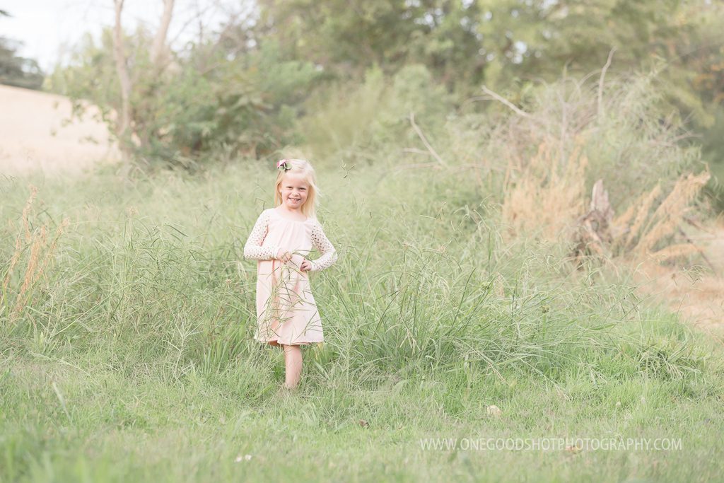 girl standng in tall grass smling