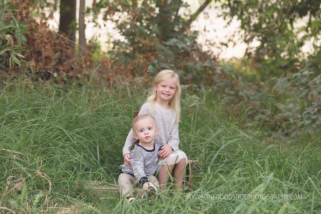 brother and sister in tall grass sitting on a box