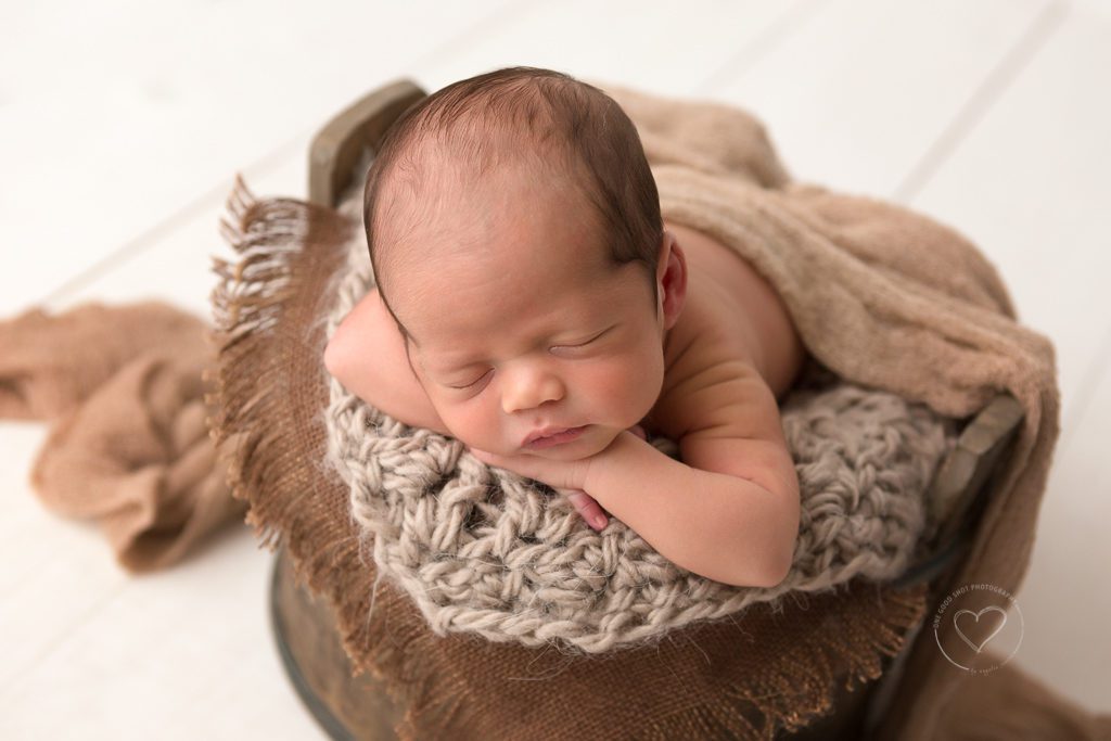 newborn boy in bucket, neutral, head on hands, Fresno newborn photographer