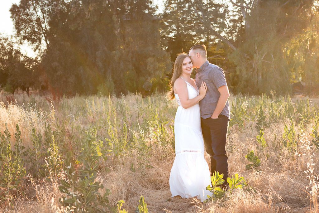 Fresno Family Photographer, husband kissing wife in a field