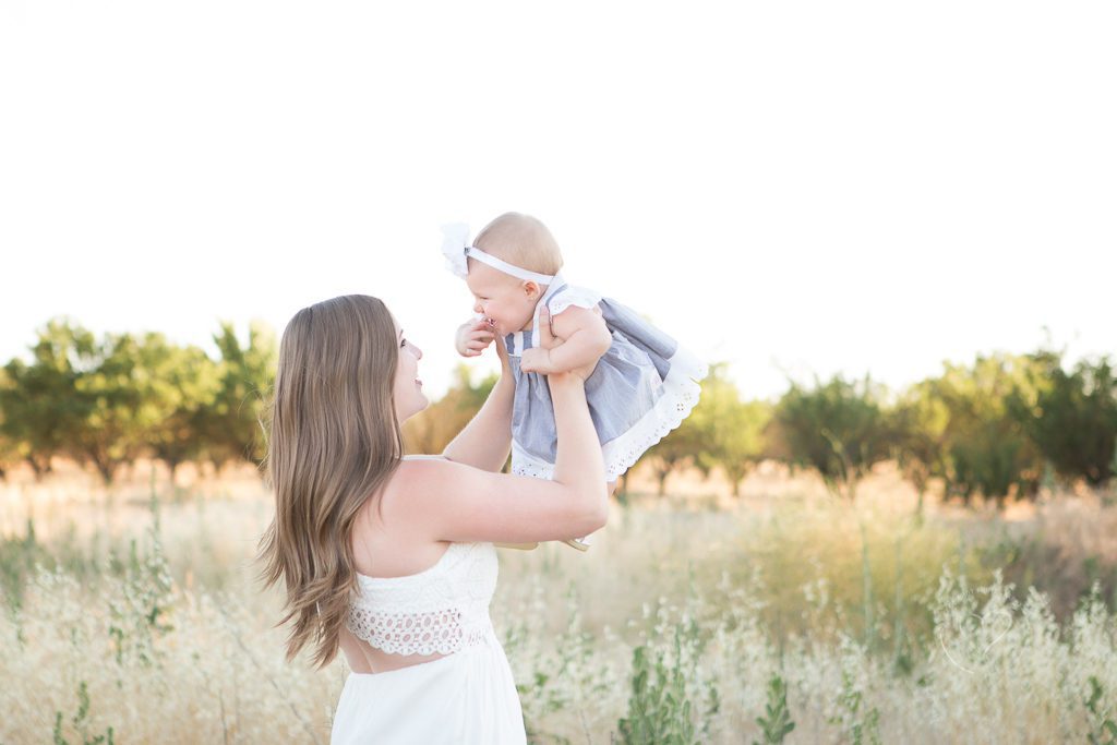 Fresno family photographer, mom holding smiling baby in the air