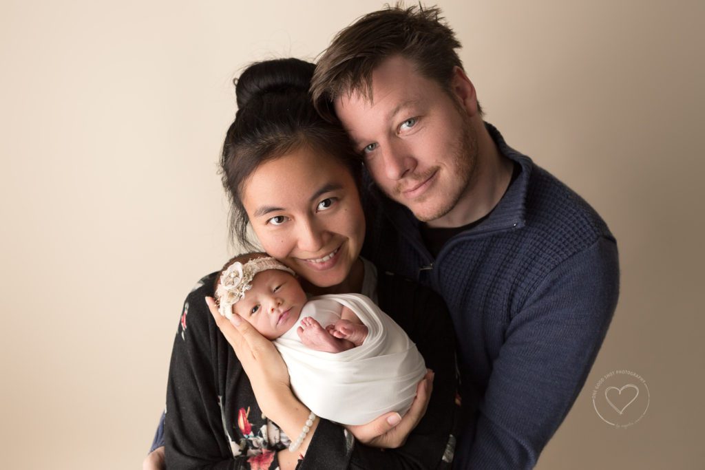 New mom and dad holding newborn girl in arms