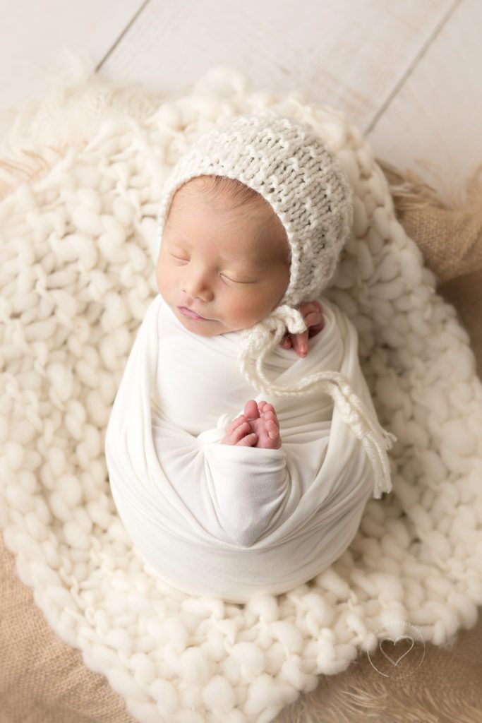 Fresno newborn photographer, baby wrapped in white, wearing cream bonnet