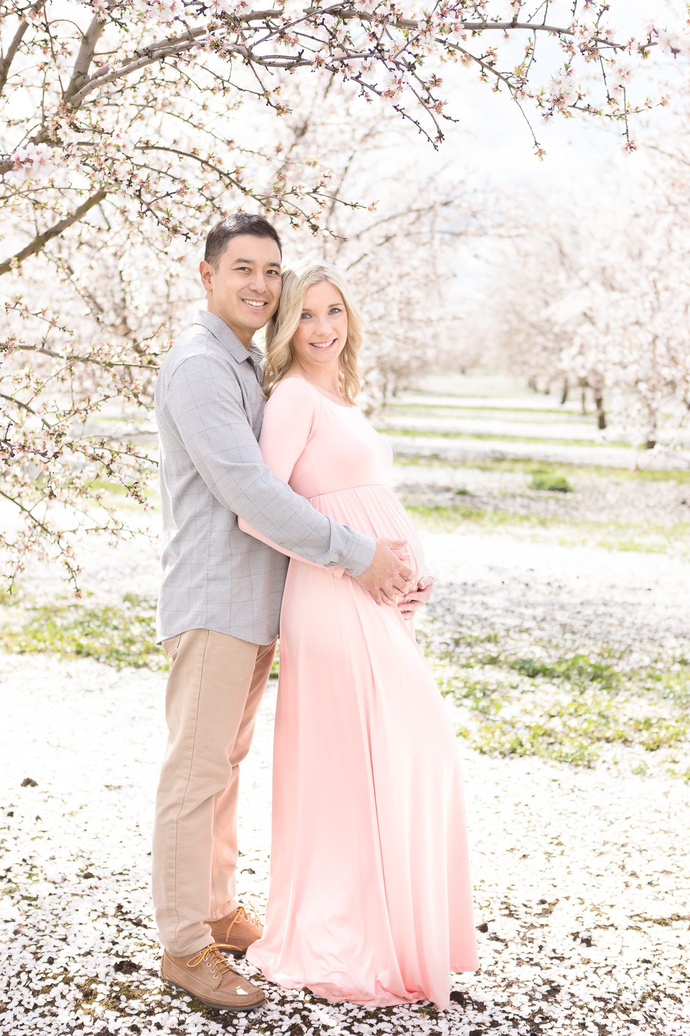 blossom maternity session, husbands arms wrapped around wives belly
