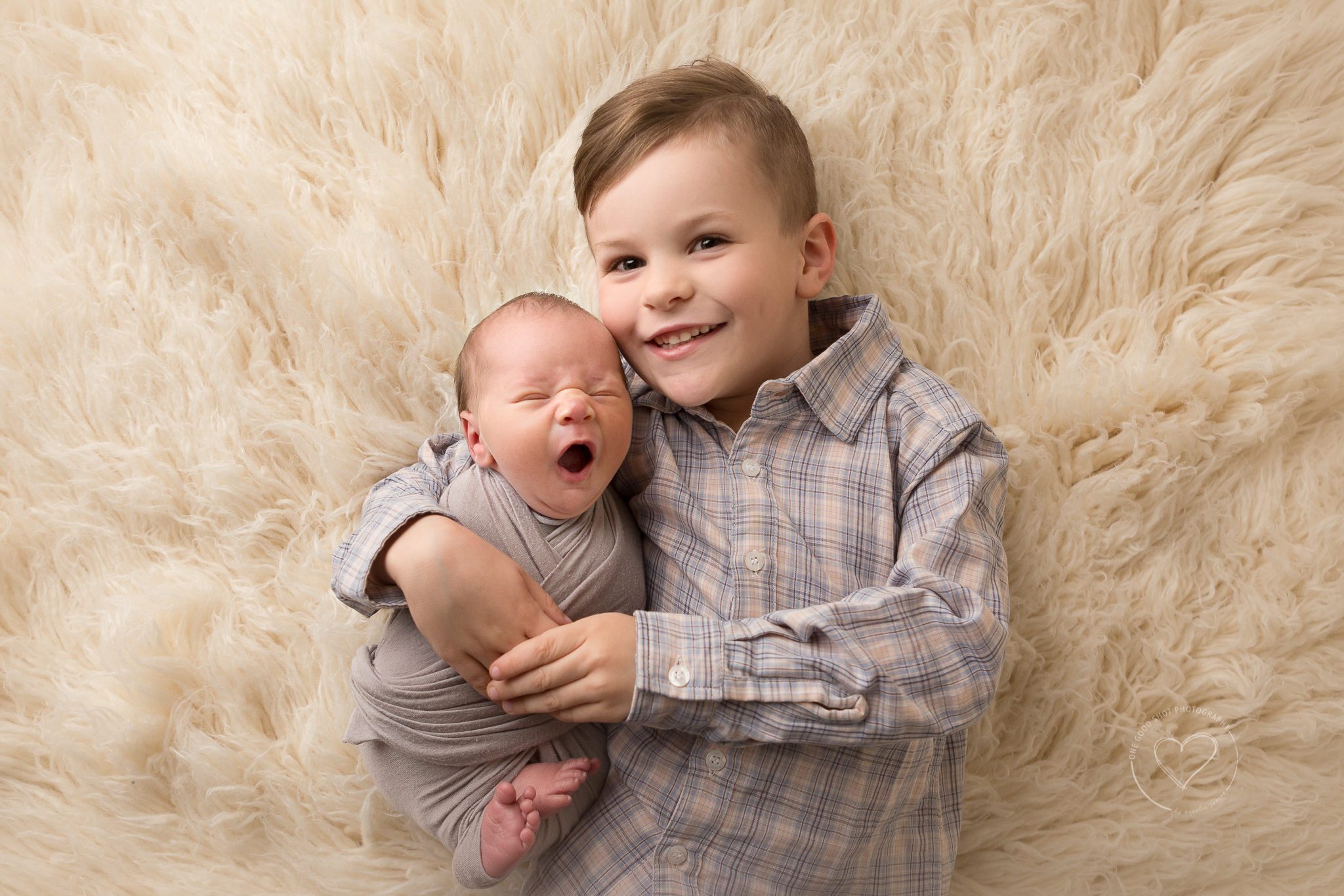 big brother holding newborn boy on flokati, Fresno Clovis, newborn photographer
