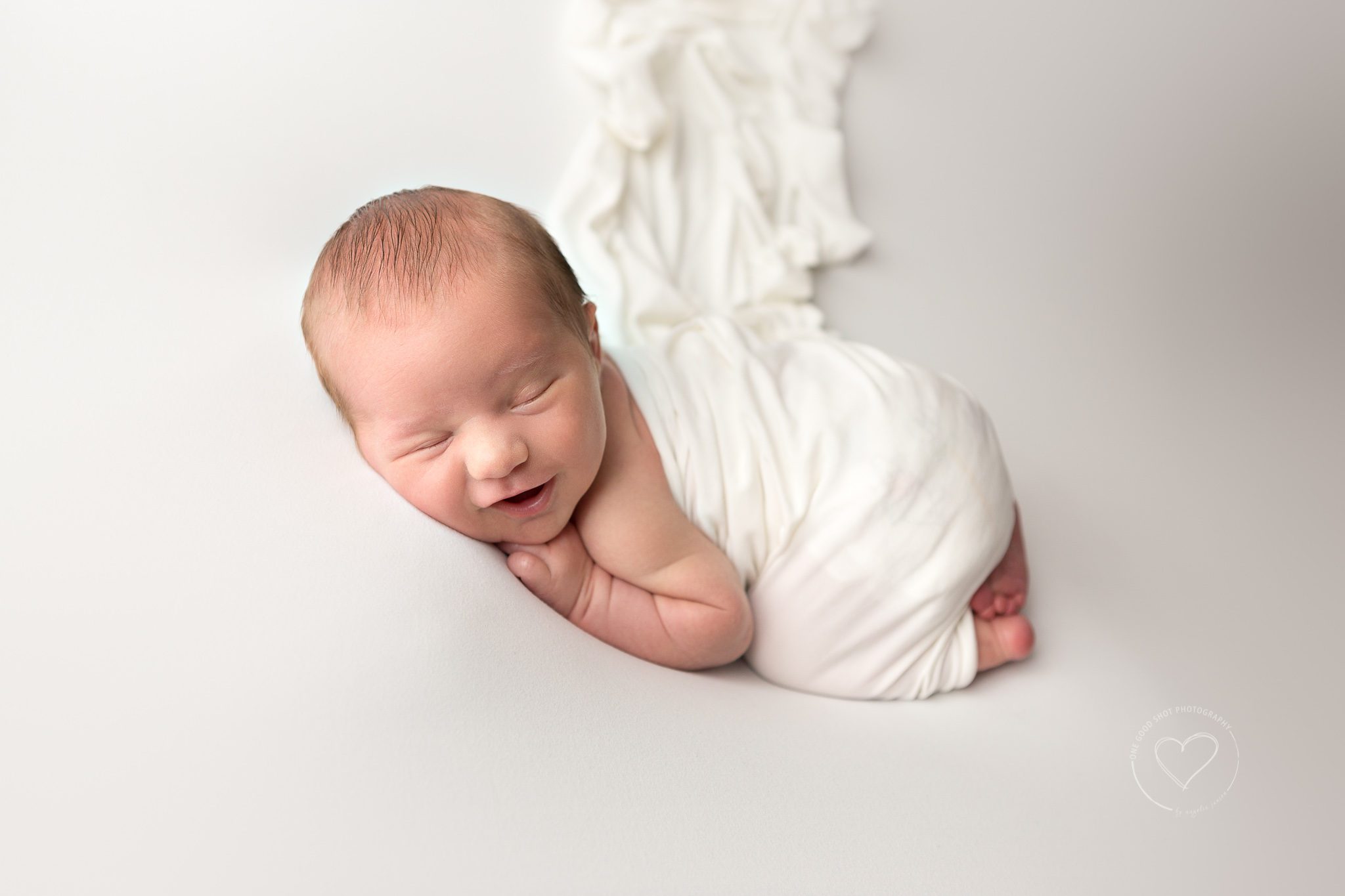 newborn boy smiling, wrapped in white, tushy up pose, Fresno, Clovis, photographer