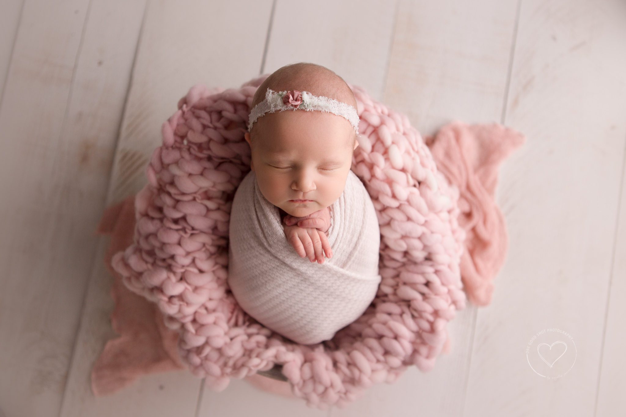 Fresno newborn photographer, baby girl, wrapped in pink laying on pink layer, floral headband