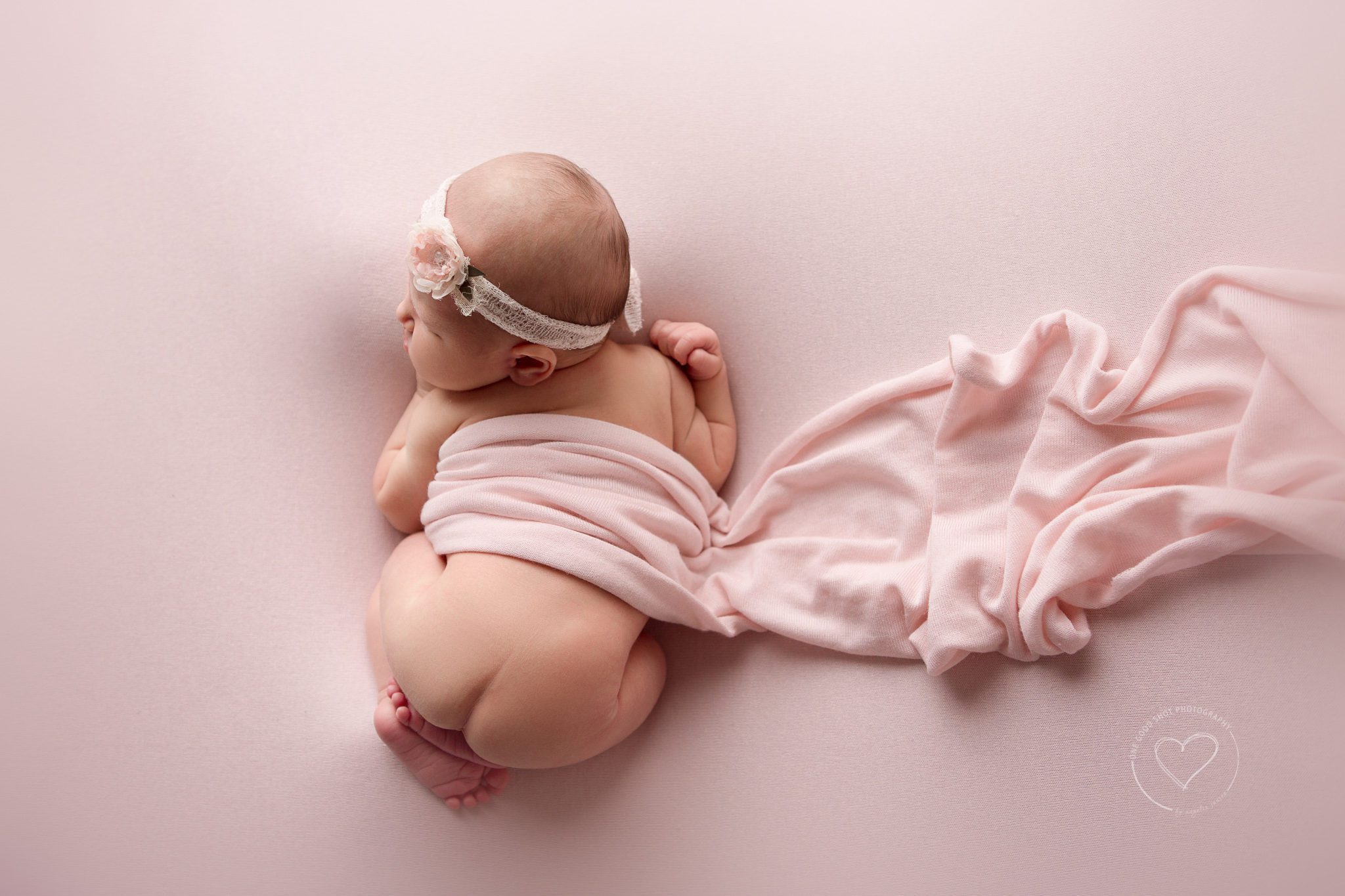 Fresno newborn photographer, tushy up pose, pink wrap, pink backdrop, floral headband, shot from above