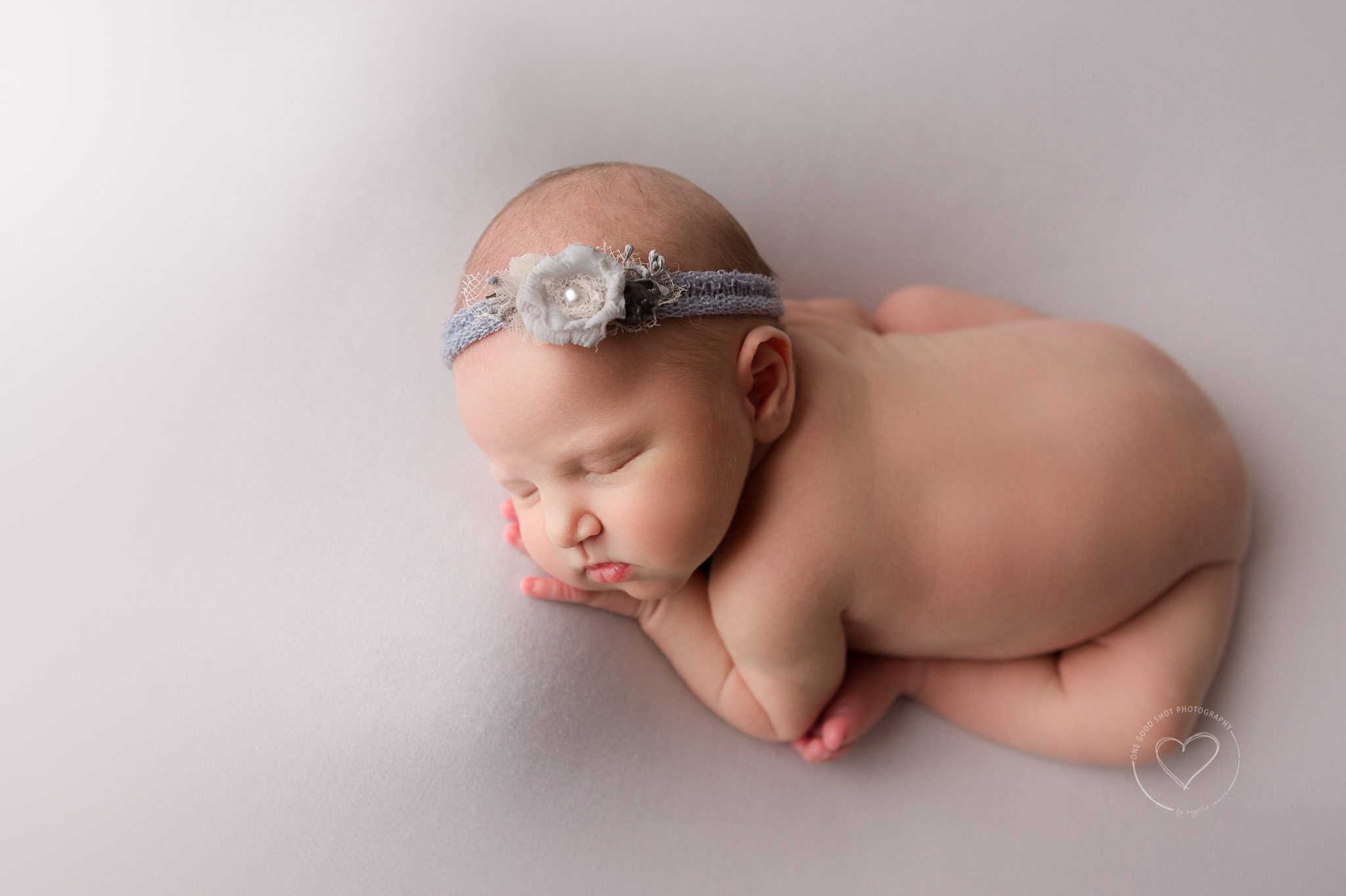 Fresno newborn photographer, taco pose, womb pose, white backdrop, blue floral headband, shot from above