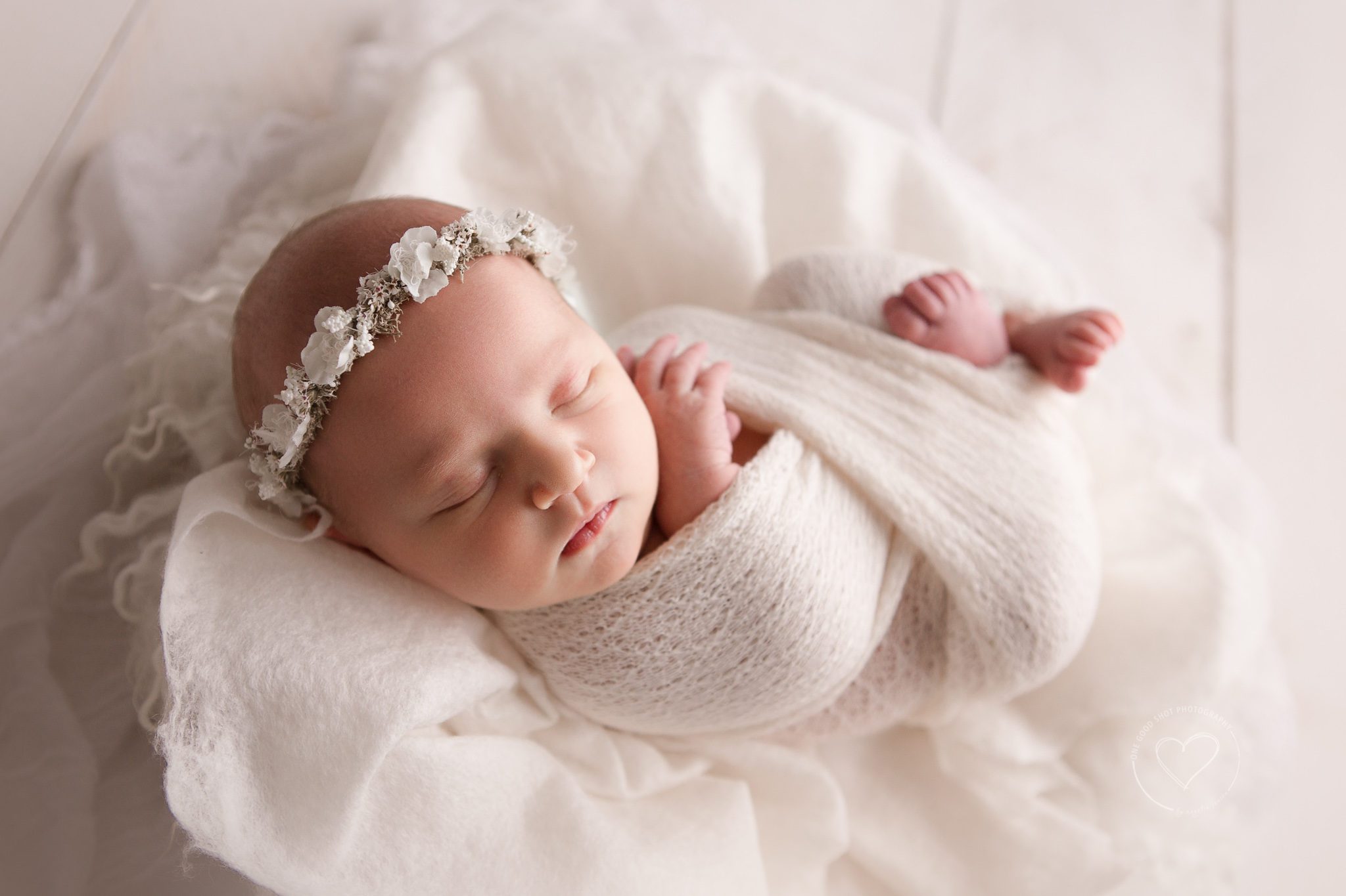 newborn photography Fresno, baby girl wrapped in white, wearing white floral halo, hands and feet showing, backlight, shooting from the shadows
