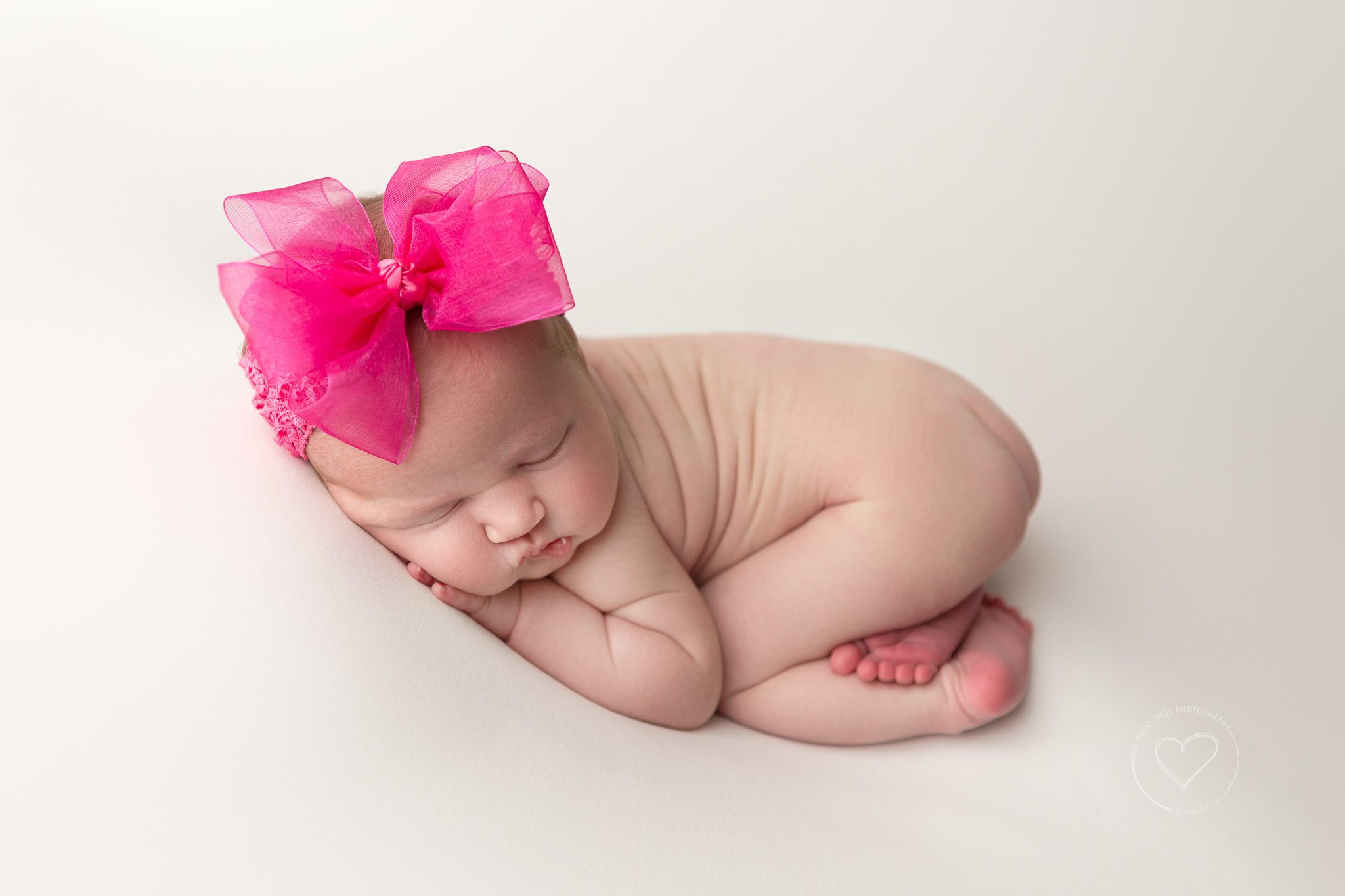 Newborn girl, tushy up, bum up pose, big hot pink bow, white background