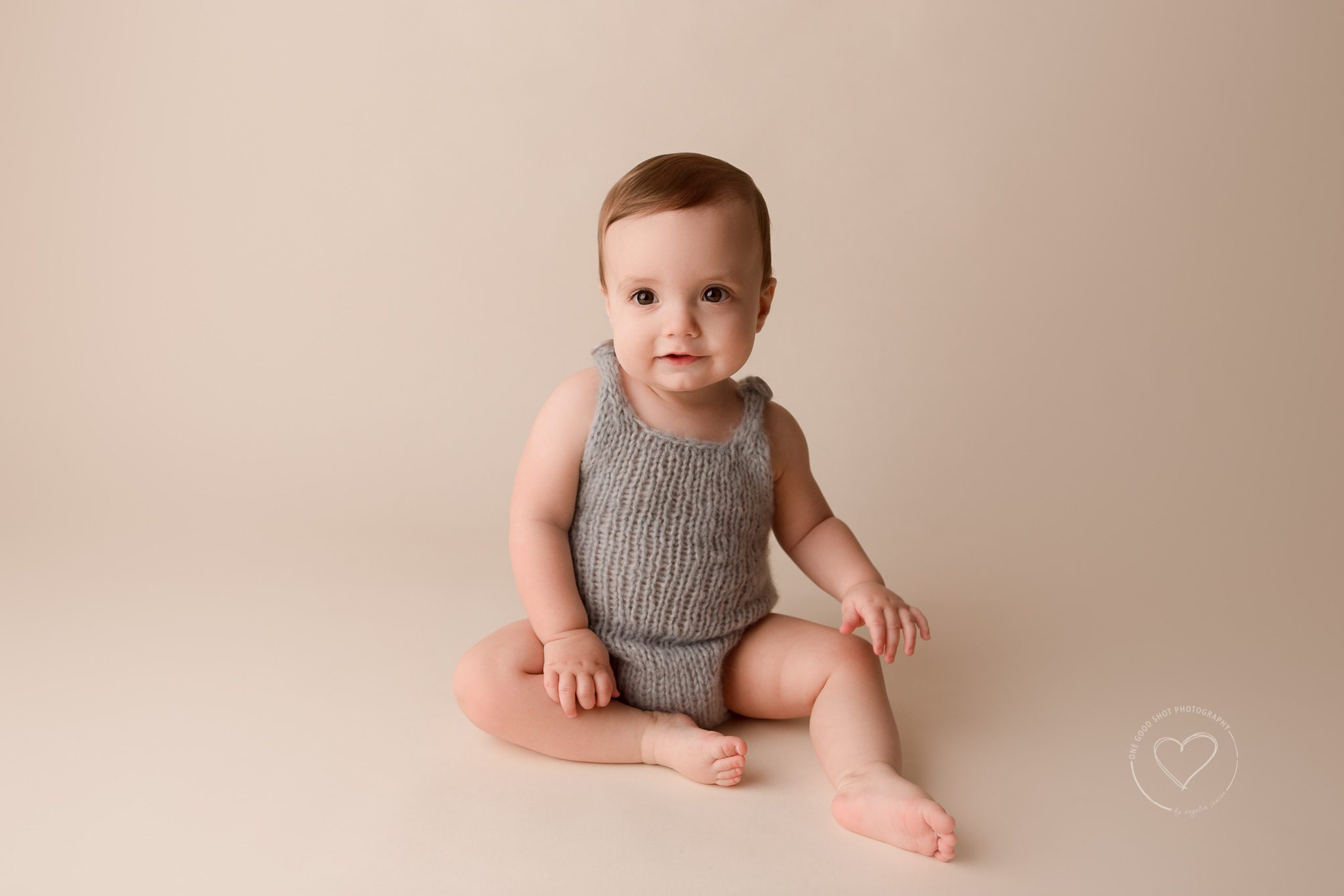 Baby photographer, baby boy wearing gray knit romper, sitting, smiling, Fresno, Clovis
