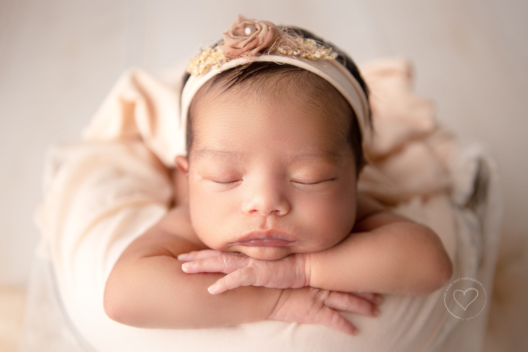 Newborn girl in a bucket, head on hands pose, peach and white, peachy floral headband