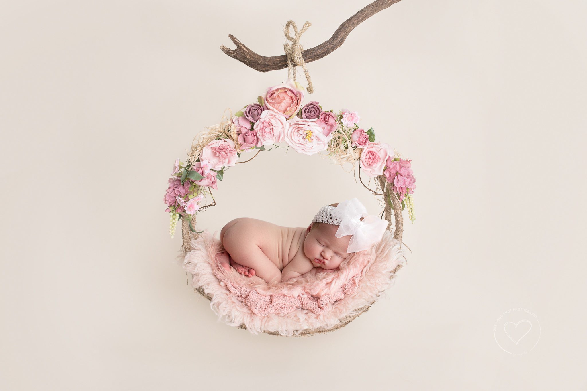 newborn baby girl, hanging in floral swing, tushy up pose, big white bow