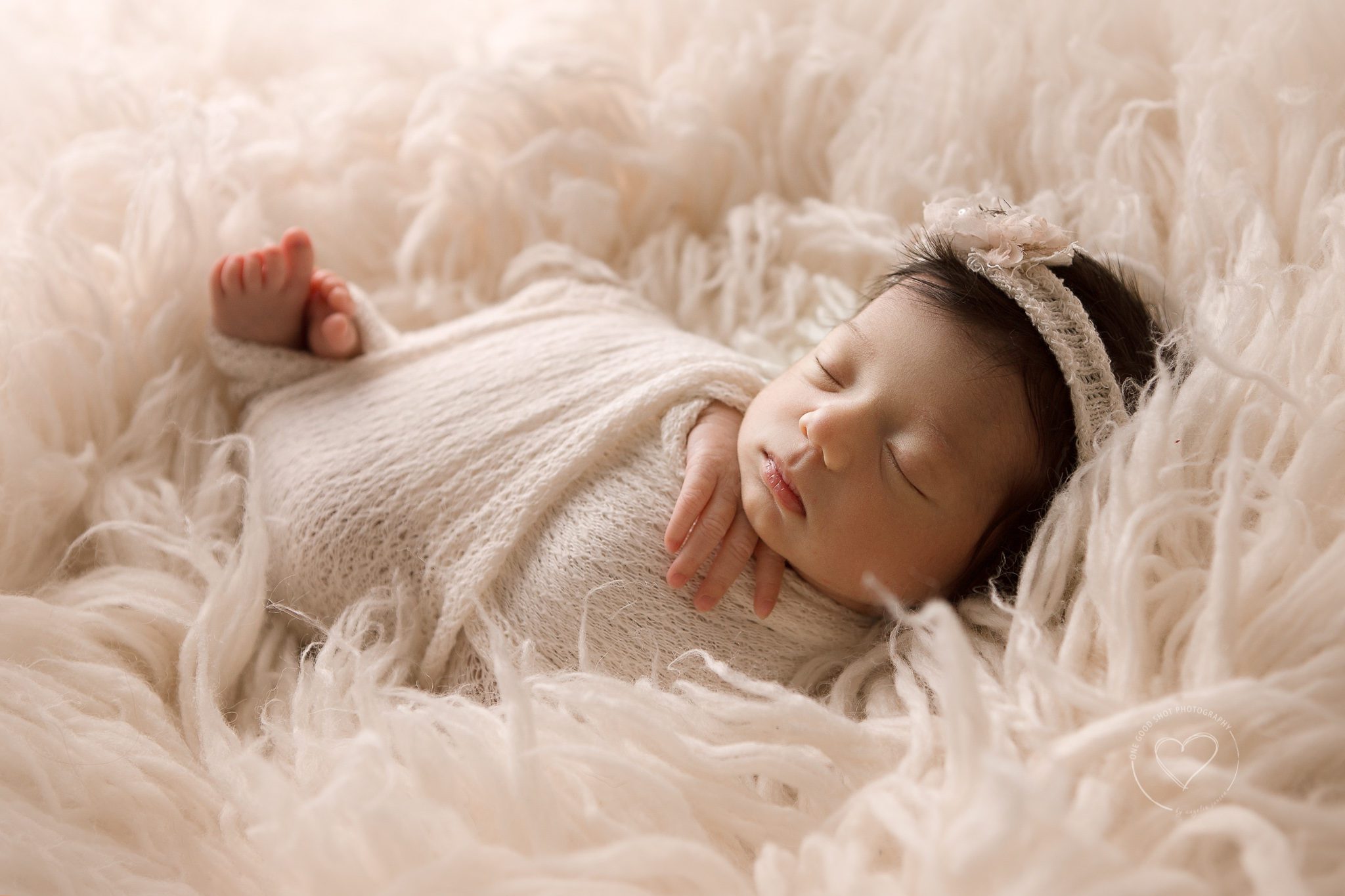 Newborn girl wrapped in cream lying on flokati rug.  fresno newborn photographer, shooting from the shadows