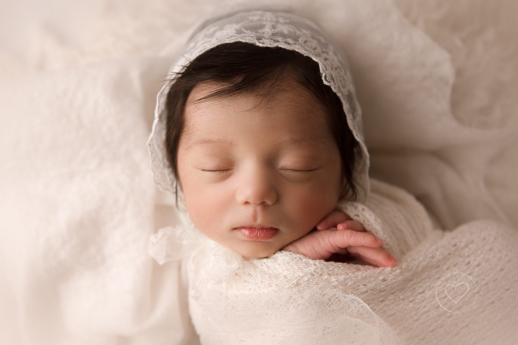 Fresno Newborn Photographer, Baby girl wearing lace bonnet, wrapped in white with hands showing
