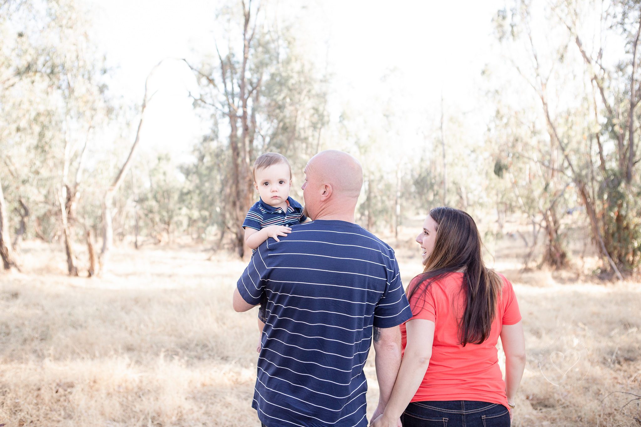 Family pictures in a field, mom and dad walking away holding hands, baby looking at camera