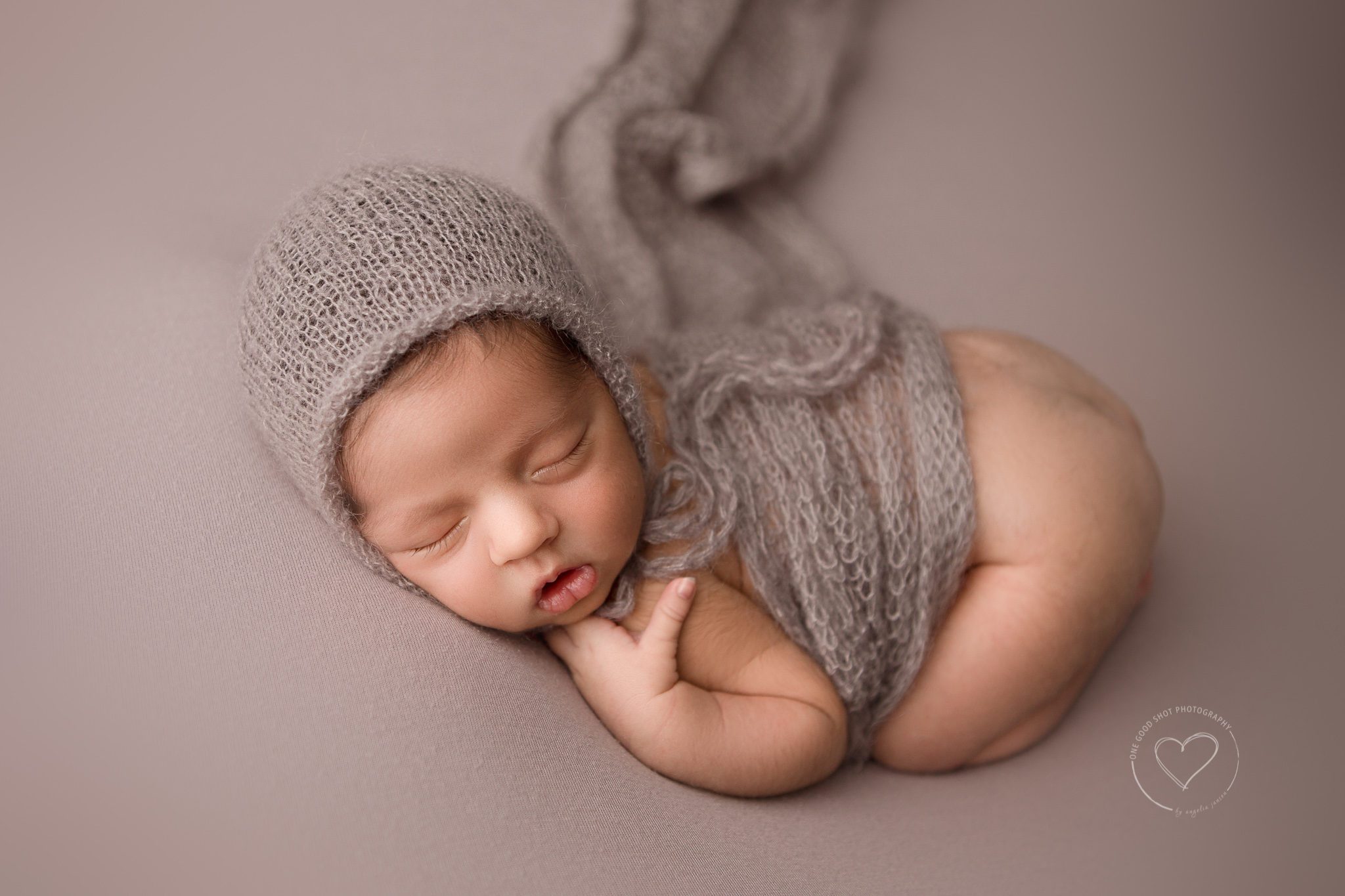 Newborn Photographer in Fresno, Baby boy in bum up pose wearing bonnet and covered with neutral wrap