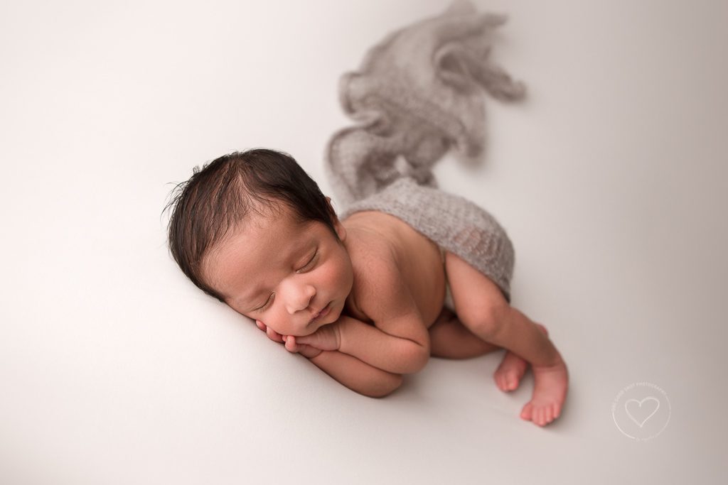 Fresno Newborn Photographer, side lying pose, has under cheeks, gray layer, white background