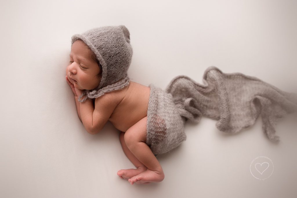 Fresno Newborn Photographer, side lying pose, hand under cheek, gray bonnet, gray layer, white background