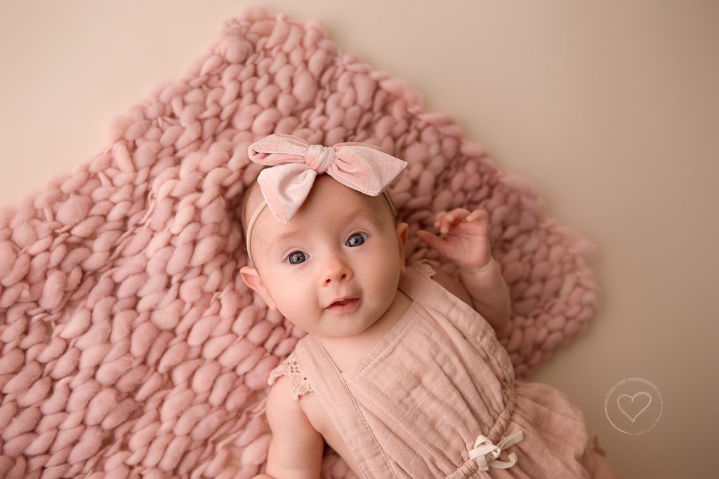 3 month old baby girl milestone photos, pink romper, pink bow, holding hands together, fresno, baby, photographer, cooing face