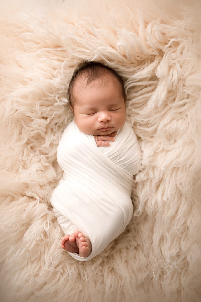 newborn photographer, fresno, Clovis, baby boy wrapped in white with hands and feet peeking out, laying on bone flokati