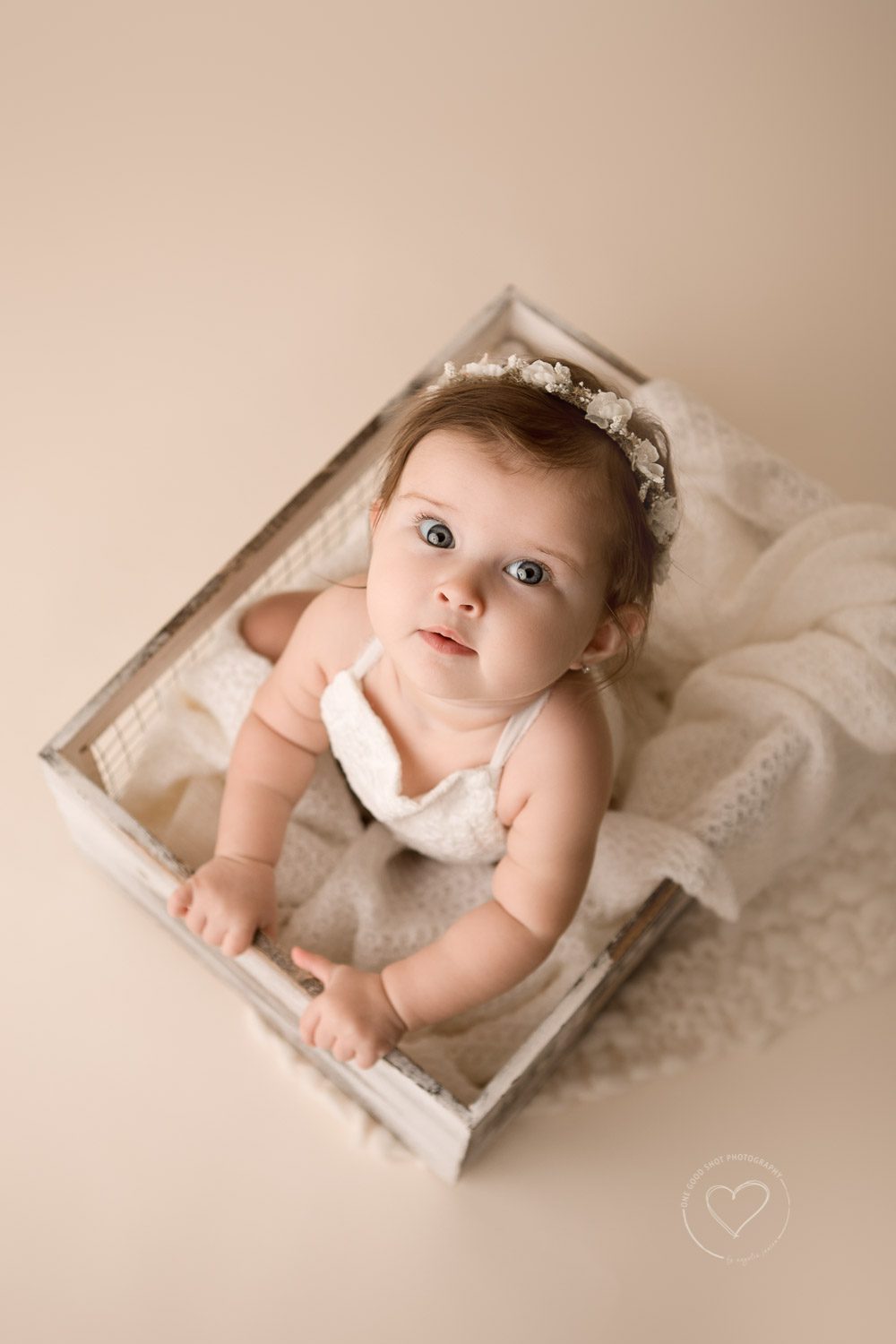 6 month girl milestone photos, sitting in box looking up at camera, neutrals, white romper, floral halo, fresno, clovis, photographer