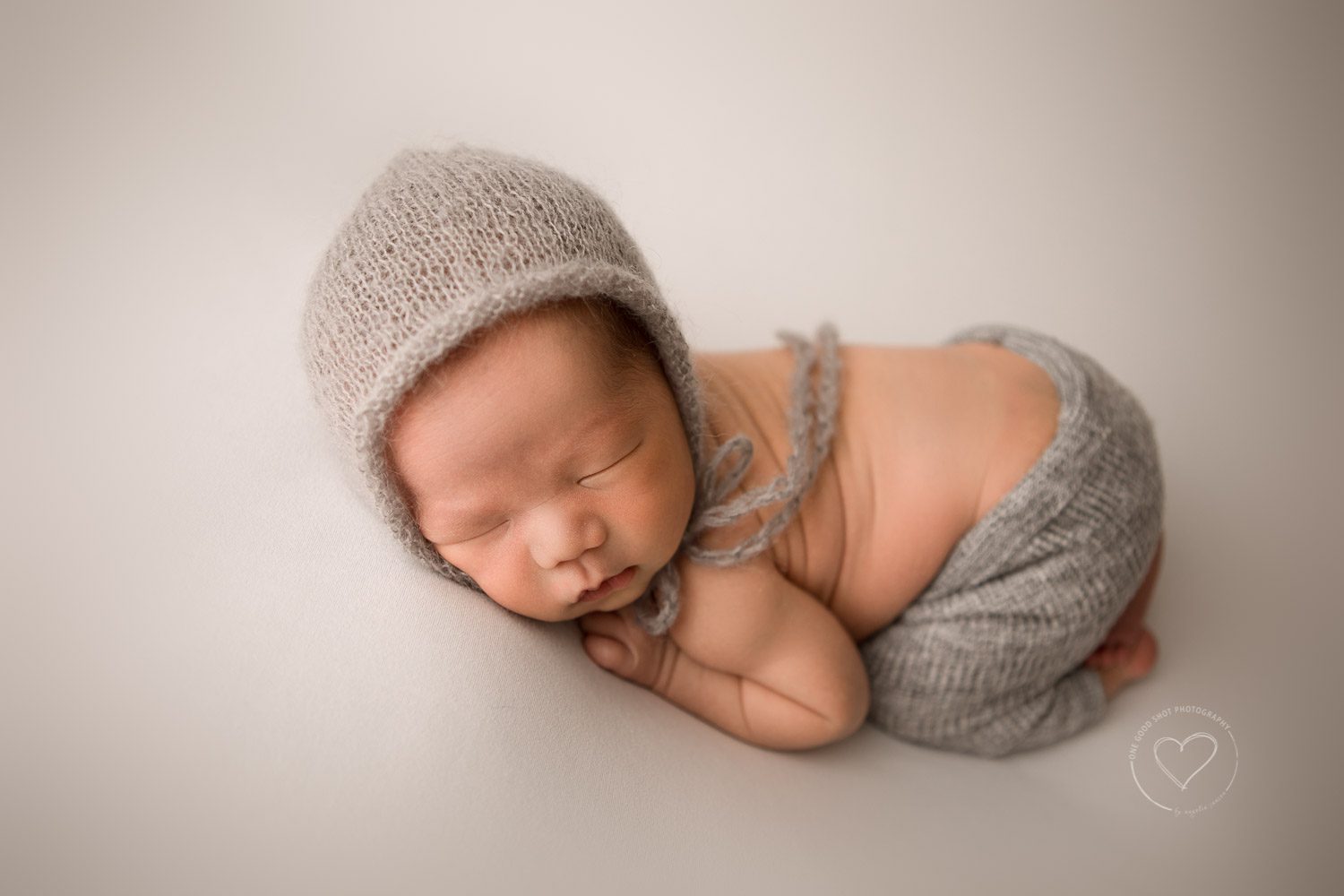 Newborn boy photos, tussle up pose, wearing gray shorts and bonnet, fresno, Clovis, photographer 