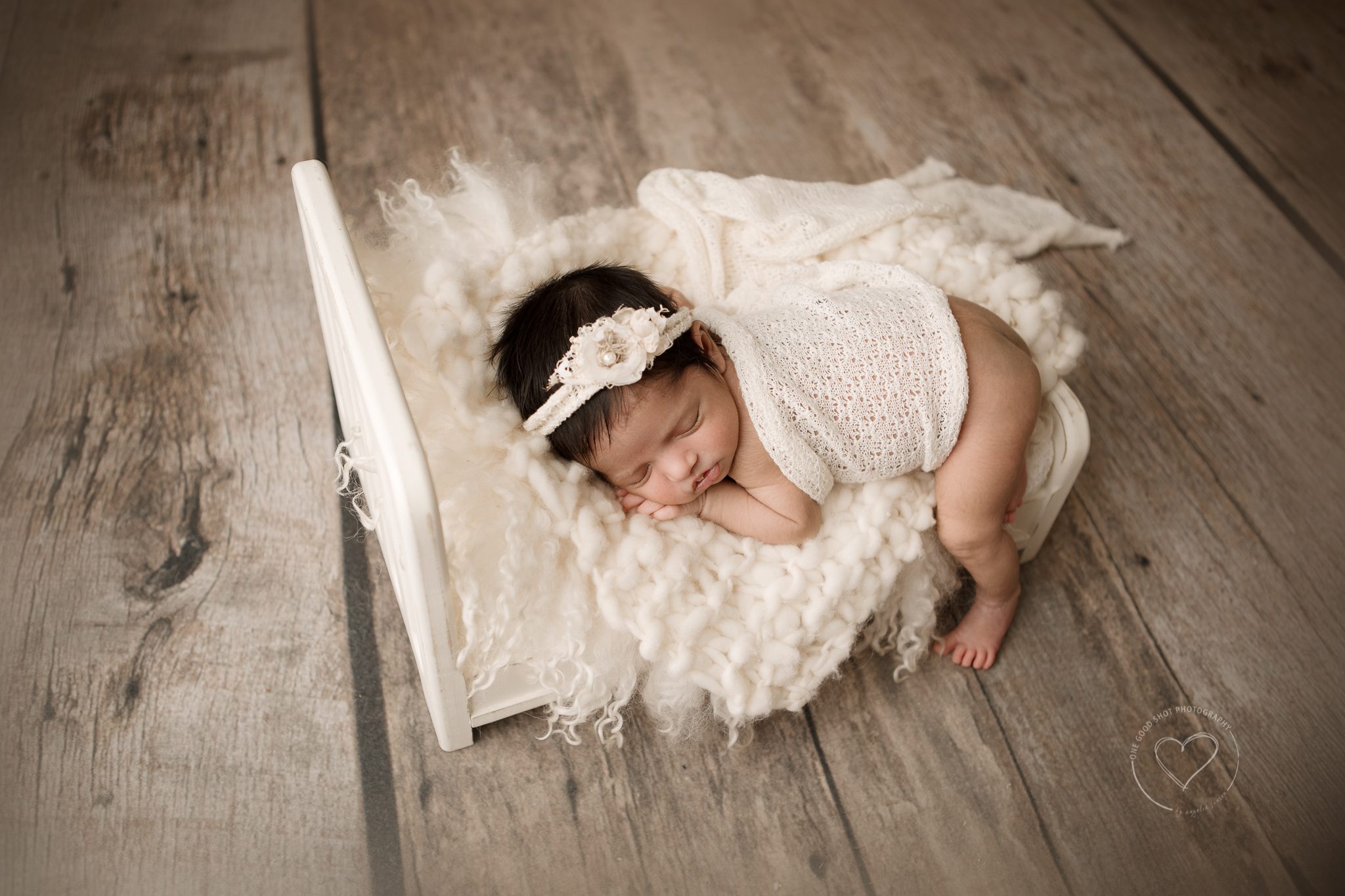 newborn baby girl, tummy pose, baby bed, cream props, wood floor, fresno photographer