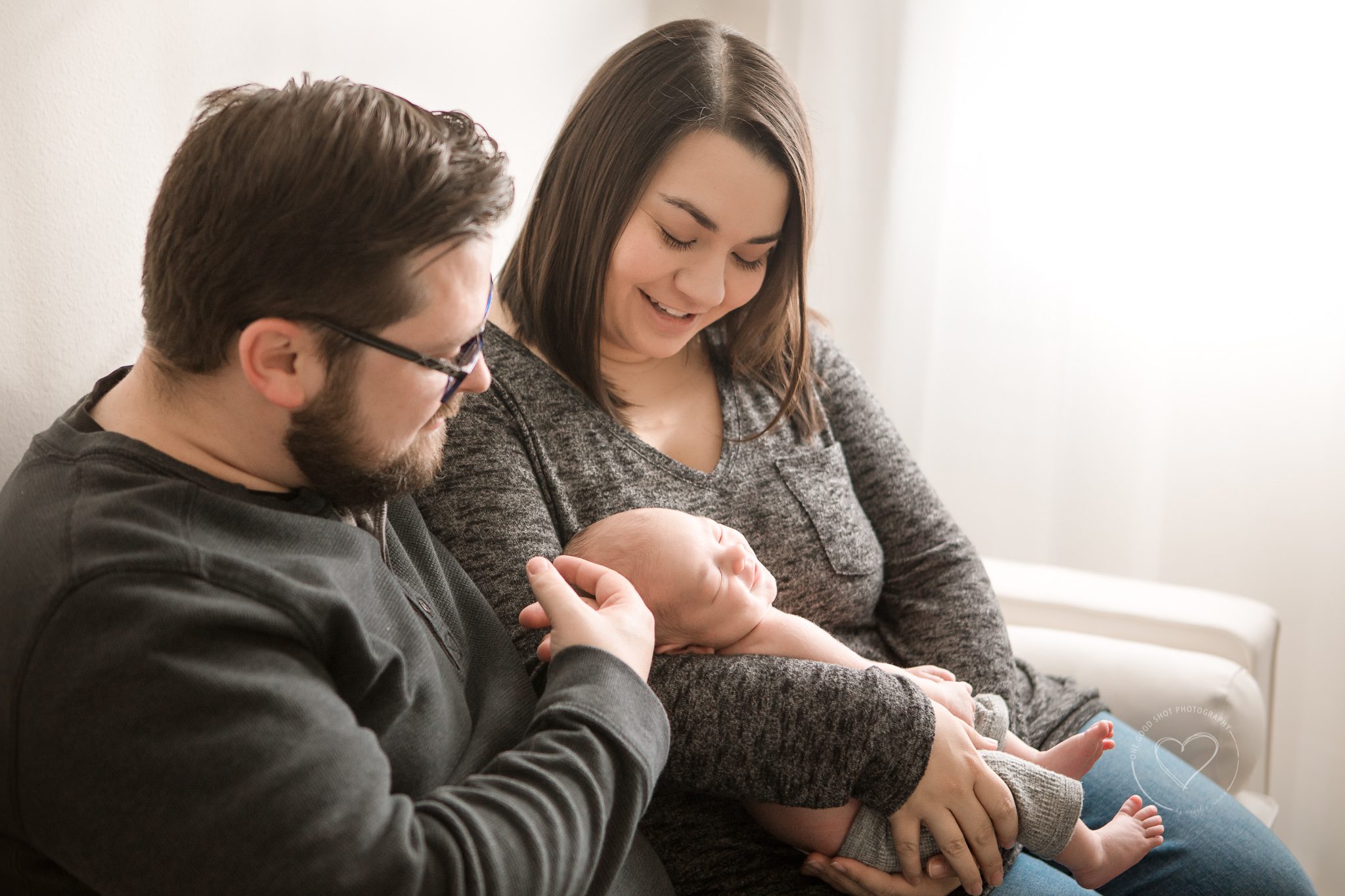 Parents snuggling newborn baby on couch, lifestyle photography, fresno