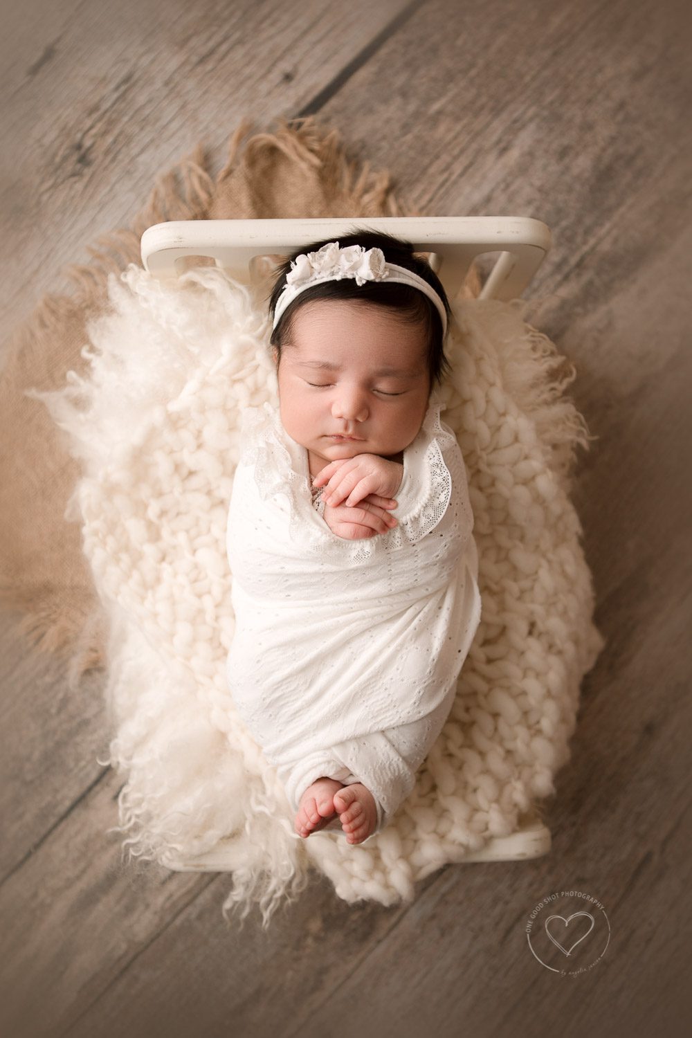 Newborn girl wrapped in white, lying in baby bed, hands and feet showing, neutral, white, Fresno Baby photographer
