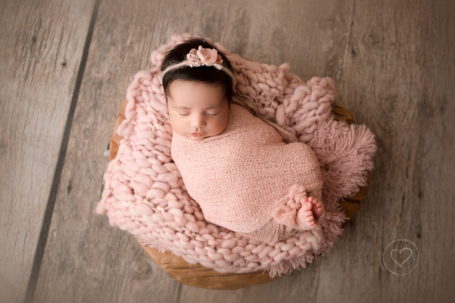 Newborn gir, pink wrap, wood floor, floral headband, Fresno photographer