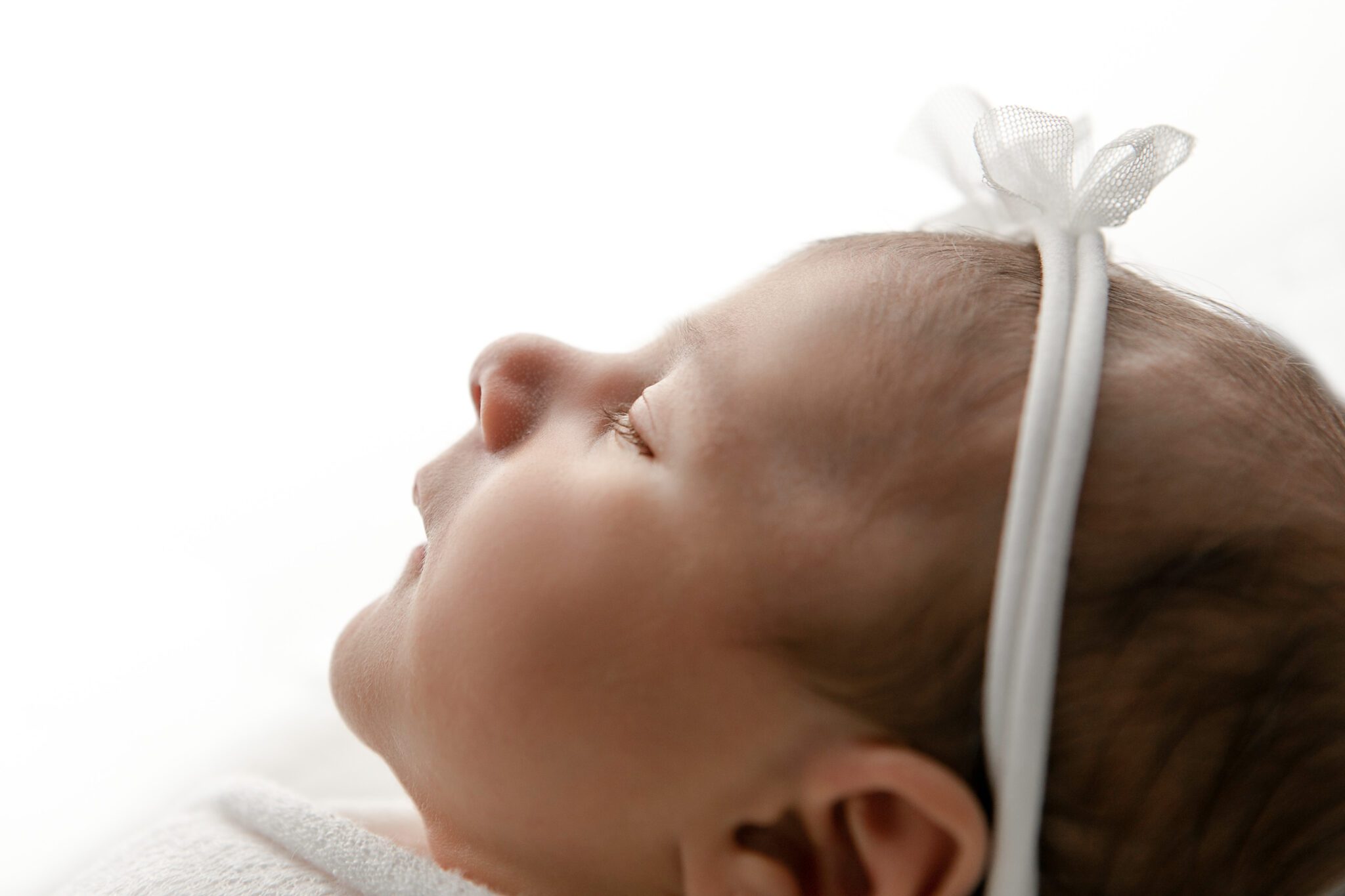 newborn baby girl side profile, high key lighting, white bow, freso photographer