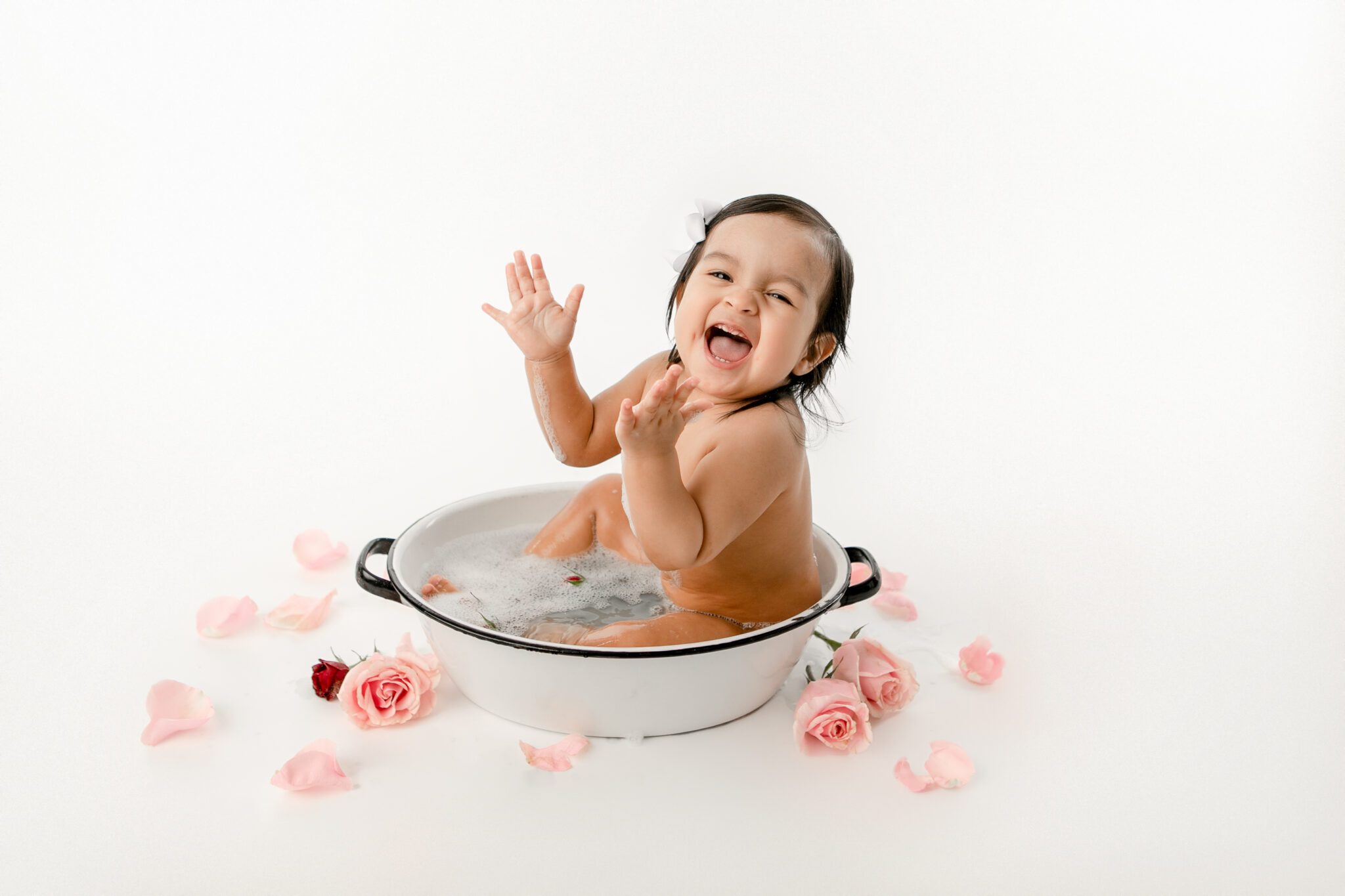 Baby in bathtub with pink flower petals with fresno baby photographer